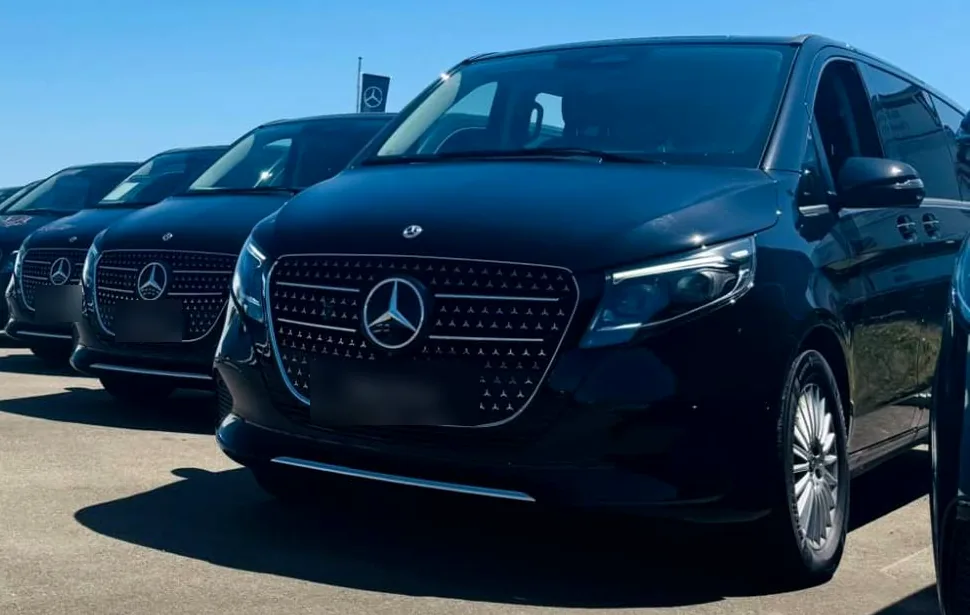 A line of black Mercedes V-Class vans parked side by side.